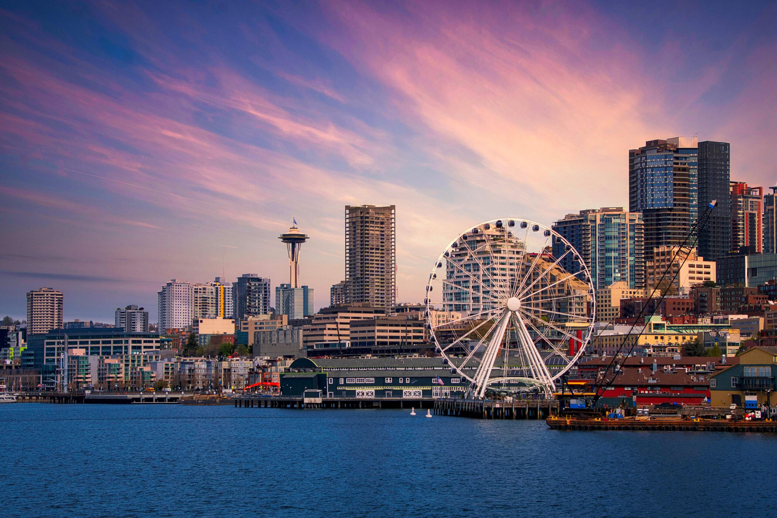 A picturesque shot of Seattle from the water, with the space needle and Ferris wheel in view.
